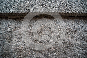 Uneven texture of rough stone wall of gray granite