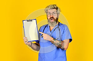 Unexpected news. mature bearded male doctor with a folder in uniform standing. Portrait of serious nurse with a folder
