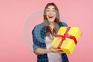 Unexpected present, holiday bonus! Portrait of surprised joyful pretty girl in checkered shirt holding wrapped box photo