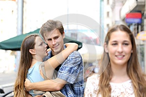 Unfaithful man hugging his girlfriend and looking another photo
