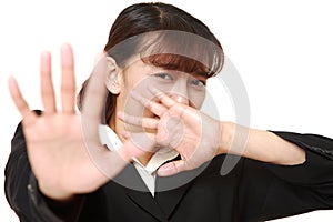 Unfashionable Asian businesswoman making stop gesture