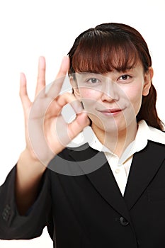 Unfashionable Asian businesswoman showing perfect sign