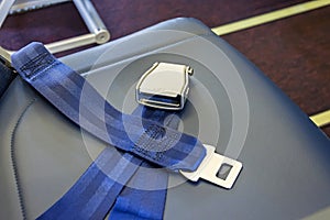 Unfastened seat belts on an empty passenger seat in an airplane