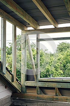 Unfinished attic wooden roof framing with vapor barrier, dormer and windows. View on timber rafters and beams on aerated concrete