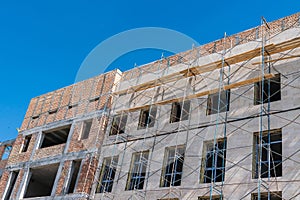 Unfinished brick building framed by scaffolding.