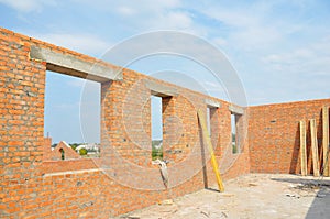 Unfinished brick house construction with windows, concrete lintels and no roof