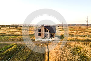 Unfinished brick house with wooden roof structure covered with metal tile sheets under construction