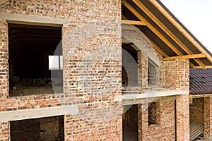 Unfinished brick house with wooden roof structure covered with metal tile sheets under construction