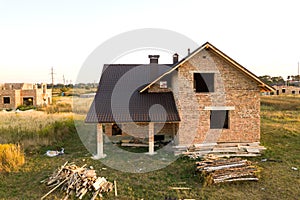 Unfinished brick house with wooden roof structure covered with metal tile sheets under construction