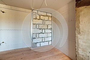 Unfinished brick wall in a room under construction prepared for drywall plates frame installation