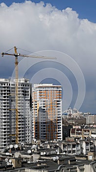 Unfinished building with construction crane jib against clouds in sky
