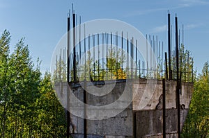 Unfinished concrete column under tower construction with protruded steel reinforcement bar and the blue nice sky background