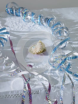 Unfinished cup cake amongst streamers on table elevated view