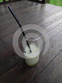 unfinished a glass of white milk on the top of wooden floor with fly and ants around