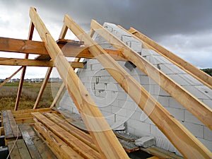 Unfinished house roofing construction with rain and rainy clouds on the sky. Wet roof beams