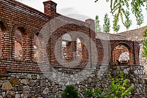 Unfinished red brick construction, old and textured stone. Large oval openings for the Windows,