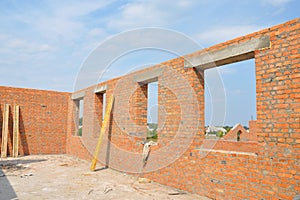 Unfinished Red Brick House Wall under Construction without Roofing. Attic Windows Concrete Lintel Frame Construction. photo