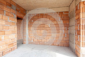 Unfinished room interior of building under construction. Brick red walls. New home