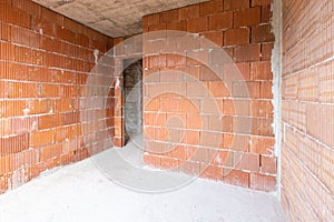 Unfinished room interior of building under construction. Brick red walls. New home