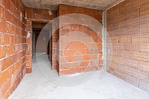 Unfinished room interior of building under construction. Brick red walls. New home