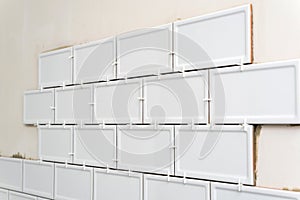 Unfinished white ceramic tiles with tile spacers. Concept of a kitchen renovation.