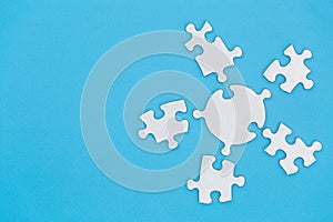 Unfinished white jigsaw puzzle on blue background with copy space. Business strategy teamwork and problem solving concept