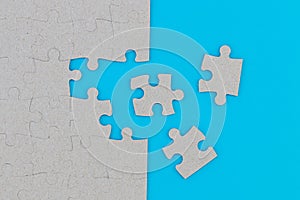 Unfinished white jigsaw puzzle pieces on blue background