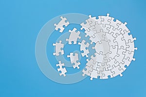 Unfinished white jigsaw puzzle pieces on blue background,  Copy space