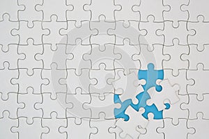 Unfinished white jigsaw puzzle pieces on blue background, The last piece of jigsaw puzzle, Copy space photo