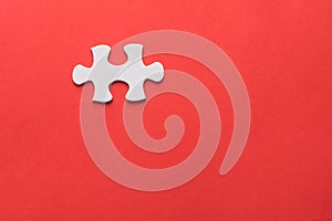 Unfinished white jigsaw puzzle pieces on red background