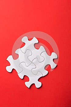 Unfinished white jigsaw puzzle pieces on red background