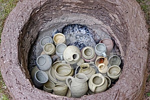 Unfired pottery pieces filled in earthen firing chamber of a primitive pit kiln
