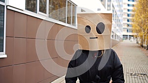 Unflappable calm crazy paper bag face walking along street. Woman wearing bread bag with emoticons