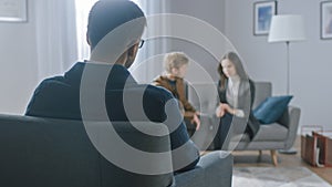 Unfocused Couple on Counseling Session with Psychotherapist. Focus on Back of Therapist Taking Notes