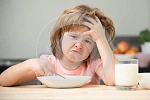 Unfocused little boy having soup for lunch. Unhappy Caucasian child sit at table at home kitchen have no appetite. Upset