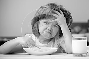 Unfocused little boy having soup for lunch. Unhappy Caucasian child sit at table at home kitchen have no appetite. Upset