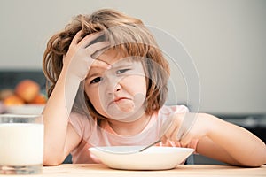 Unfocused little boy having soup for lunch. Unhappy Caucasian child sit at table at home kitchen have no appetite. Upset