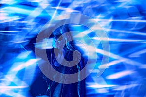 Unfocused portrait of young beautiful girl in leather jacket posing over blue background with abstract neon elements.