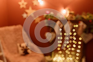 Unfocused shot. Blurry Christmas background with arm-chair and fireplace decorated with hanging socks, fir branches