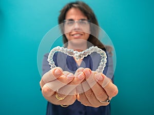 AN UNFOCUSED WOMAN HOLDS A HEART-SHAPED INVISALING BRACES photo
