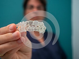 AN UNFOCUSED WOMAN HOLDS AN INVISALING BRACES photo