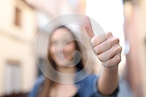 Unfocussed woman gesturing thumb up in the street