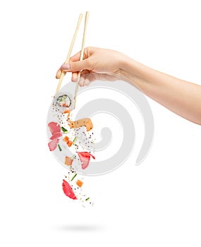 Unfolded sushi roll with ingredients chopsticks in female hand on white background