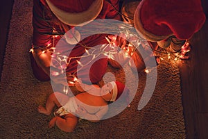 Unfree parents with a baby on New Year Eve. A family with a newborn at the Christmas tree in the evening living room