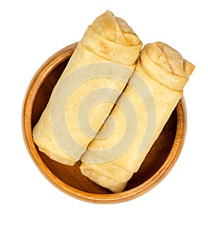 Unfried spring rolls, ready to fry, in a wooden bowl