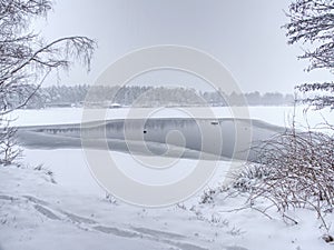 Unfrozen lake in winter forest. Black water and snowy brunches