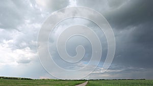 Ungraded Dramatic Sky With Rain Clouds On Horizon Above Rural Landscape Country Road Through Field. Agricultural And