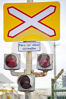 Unguarded level crossing traffic sign for trains.  3 traffic lights.  information panel, "pare ao sinal vermelho"