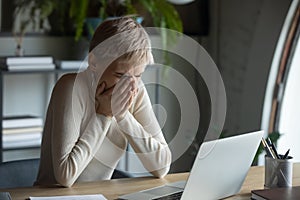 Unhappy 30s lady covering mouth with hands sneezing or coughing.