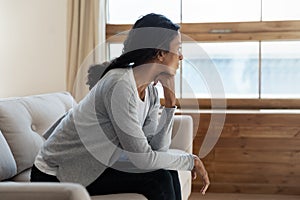 Unhappy african american girl sit on sofa at home